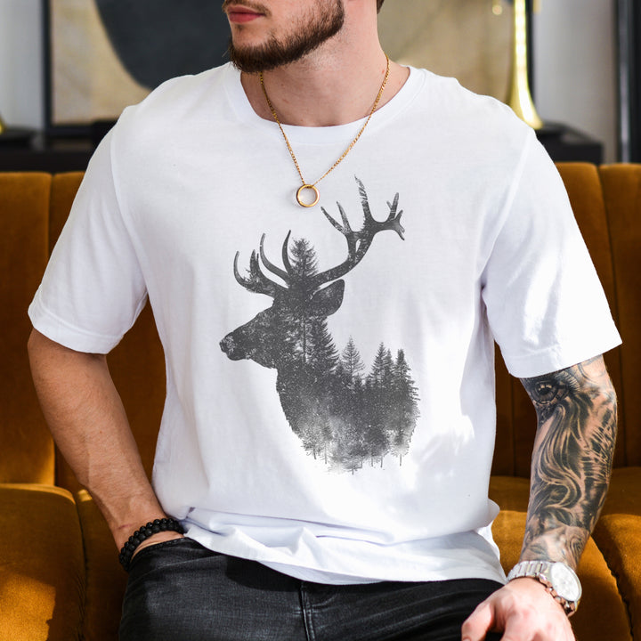 a man sitting on a couch wearing a white shirt with a picture of a deer