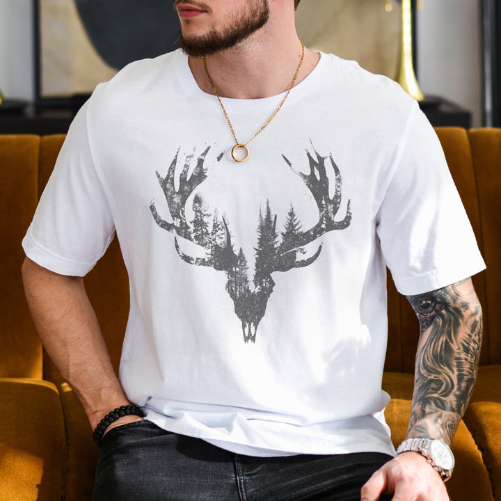 a man sitting on a couch wearing a white shirt with a deer head on it